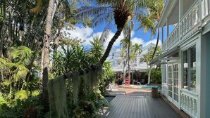 A wooden deck with lush greenery and a pool area. - Douglas House - Adults Only (Key West)
