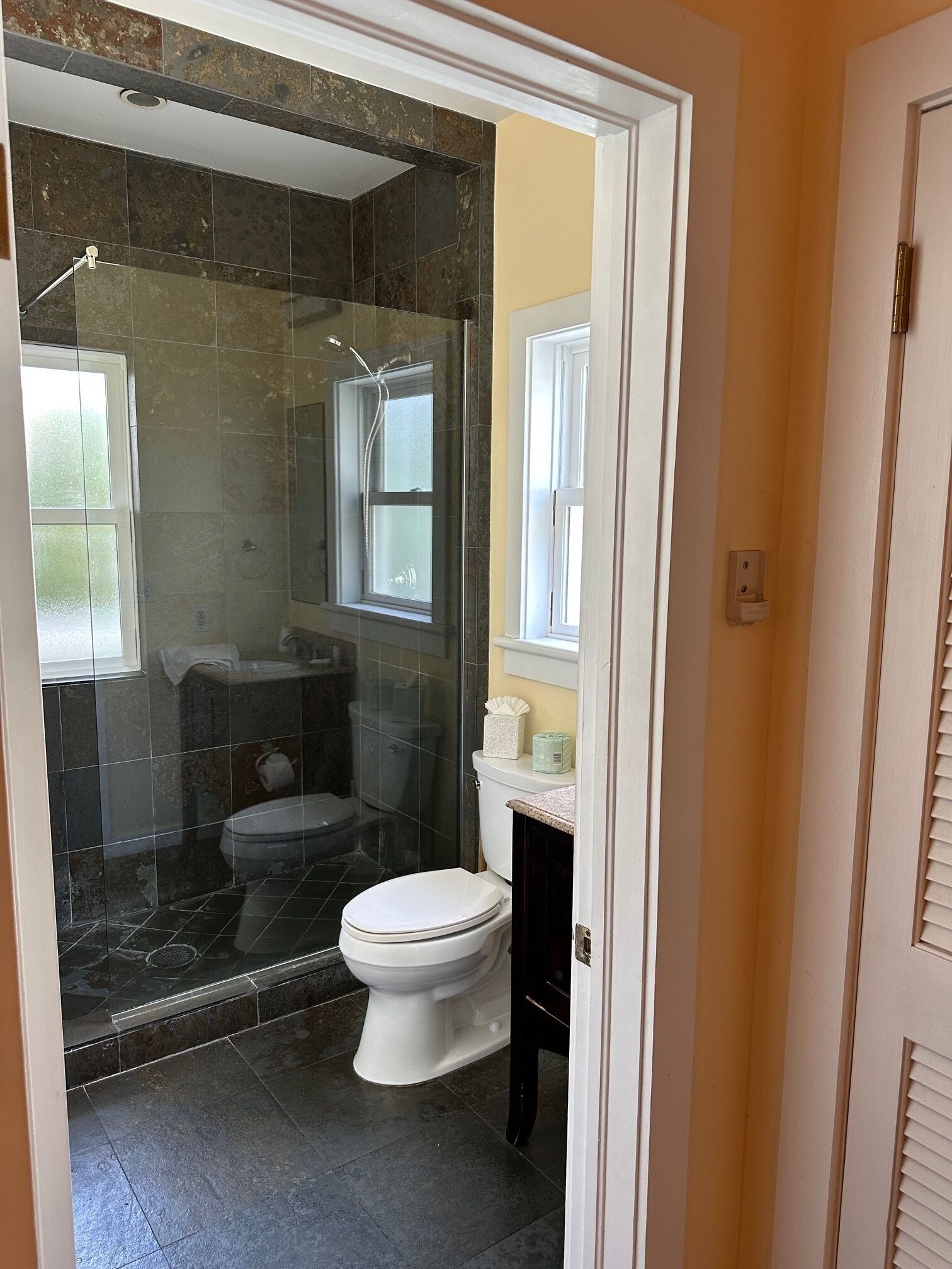 A bathroom with a glass-enclosed shower, a toilet, and a sink.