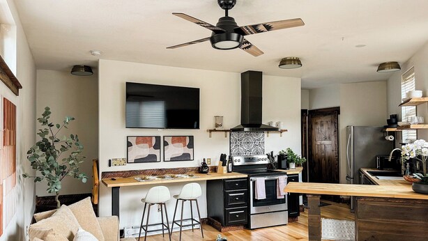 Une cuisine moderne dotée d’un îlot central, d’un coin repas avec un canapé et des chaises, et d’un ventilateur de plafond.