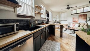 Une cuisine moderne dotée d’un four à micro-ondes encastré, de meubles de couleur noire et d’un plan de travail en bois.