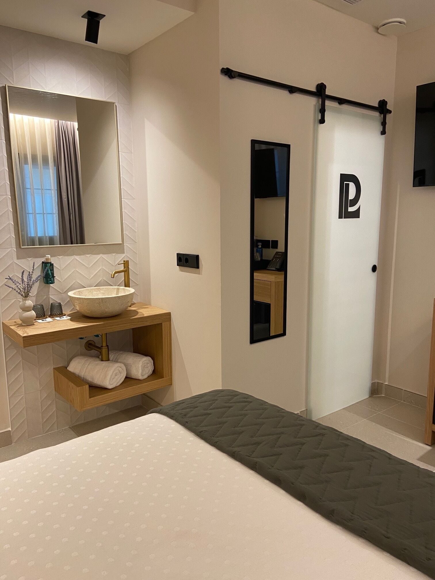A modern bathroom with a large mirror, a sink, and a towel rack.