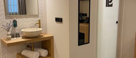 A modern bathroom with a large mirror, a sink, and a towel rack.