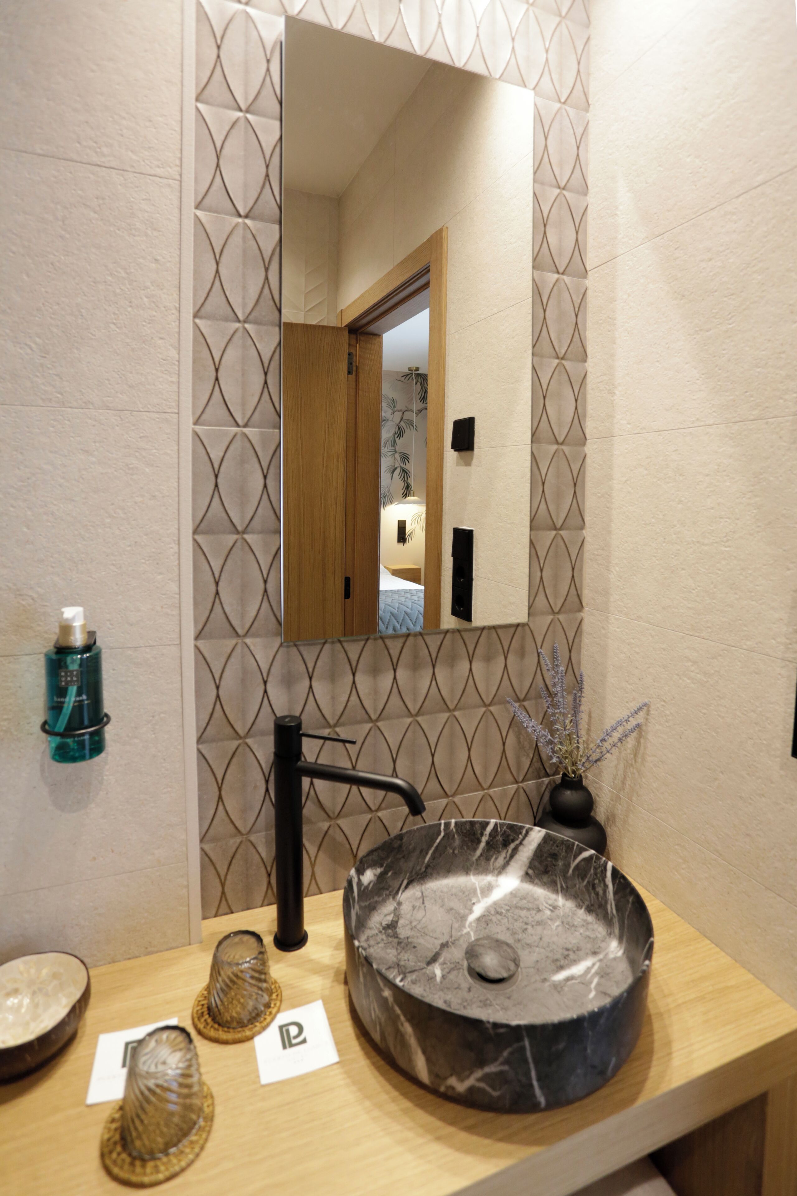 A bathroom with a round sink, a mirror, and a towel rack.
