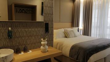 A hotel room with a bed, bedside table, and a mirror.