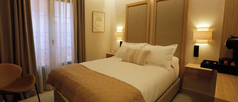 Una habitación de hotel con una cama grande, una silla, una mesita de noche y una lámpara.