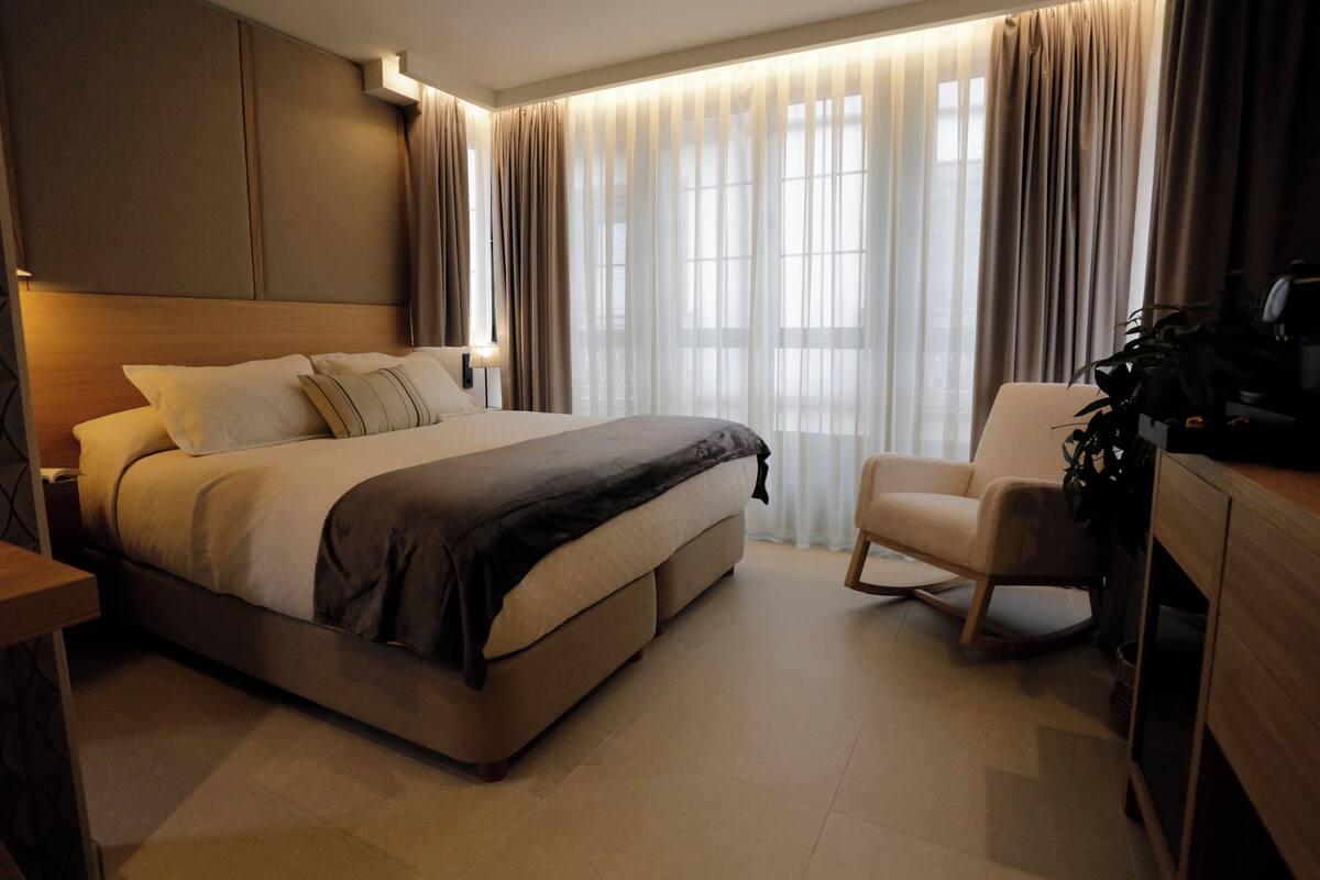 Ein modernes Hotelzimmer mit einem großen Bett, einem Schreibtisch und einem Stuhl.