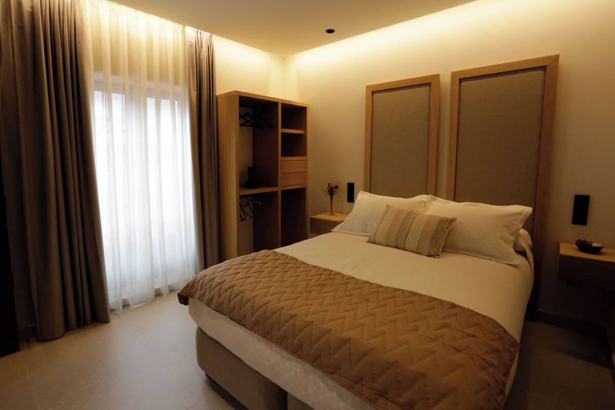 Ein Hotelzimmer mit Bett, Kleiderschrank, Nachttisch und Spiegel.