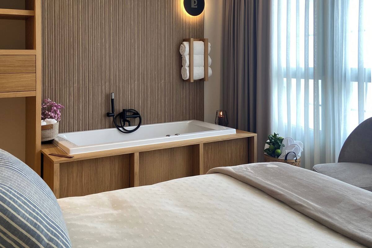 Ein modernes Badezimmer mit einem Holzlager, einer großen Badewanne und einem Wandhandtuchhalter.