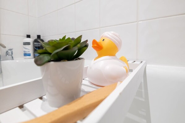 A bathtub with a rubber duck and a potted plant. - Host Stay Good Vibes at Buckingham (Brighton)