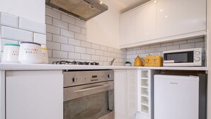 Une cuisine moderne avec des meubles blancs, un four encastré, un four à micro-ondes et un réfrigérateur.