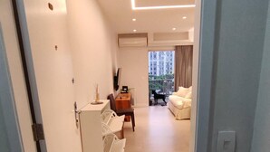 A modern living room with a sofa, a coffee table, and a dining area with chairs and a table. - Estácio Subway, 3 Bedrooms, AC, Garage (Estácio Rio de Janeiro)