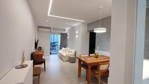 A modern hotel room with a dining area, a sofa, a TV, and a balcony with a view of the city. - Estácio Subway, 3 Bedrooms, AC, Garage (Estácio Rio de Janeiro)