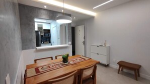 A dining area with a wooden table, chairs, a bench, a white cabinet, and a hanging light fixture. - Estácio Subway, 3 Bedrooms, AC, Garage (Estácio Rio de Janeiro)
