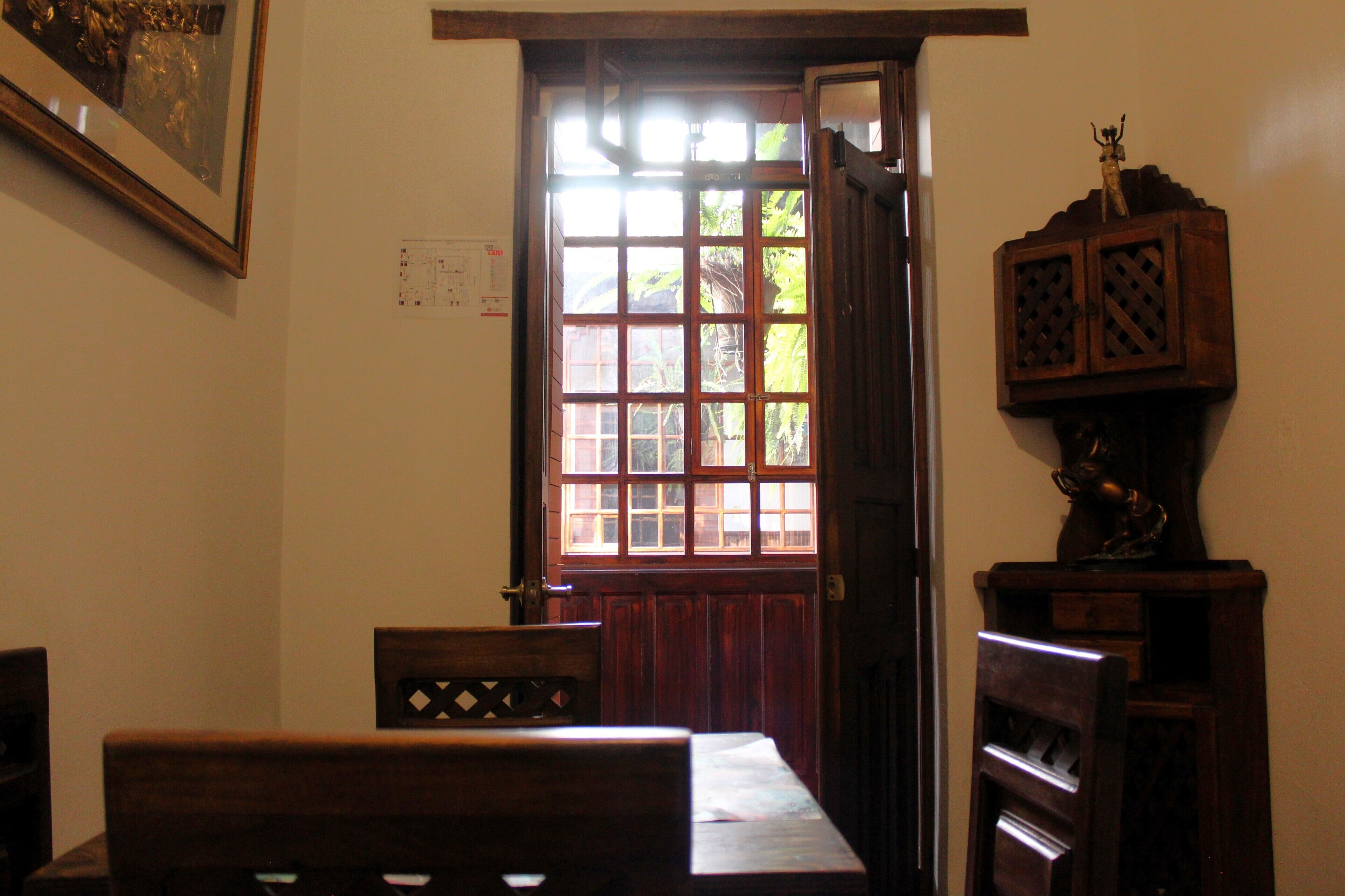 A room with a wooden door, a wooden cabinet with a decorative top, and a framed picture on the wall.