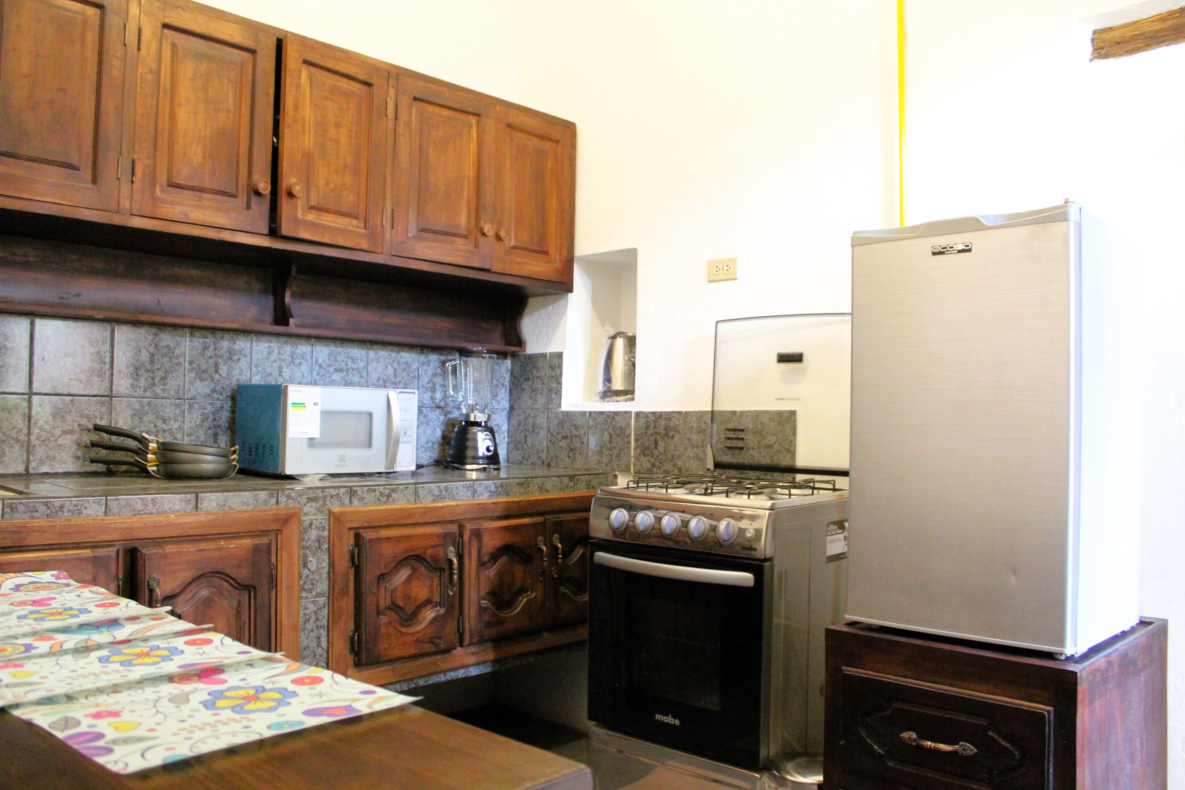A kitchen with wooden cabinets, a stove, a microwave, and a refrigerator.