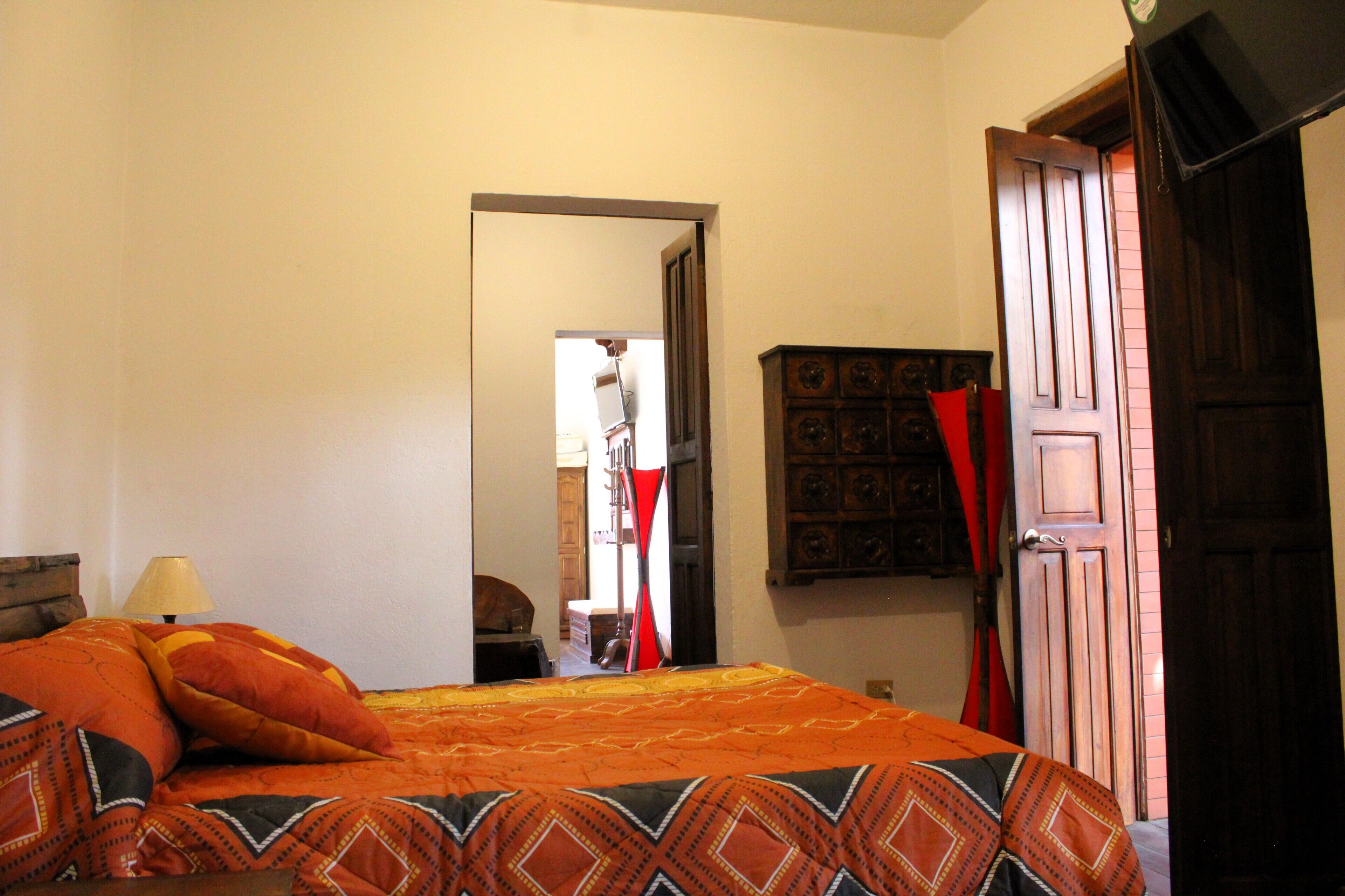 A bedroom with a bed, a wooden wardrobe, and a door.