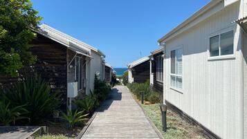 A row of cabins with a wooden walkway leading to the beach.