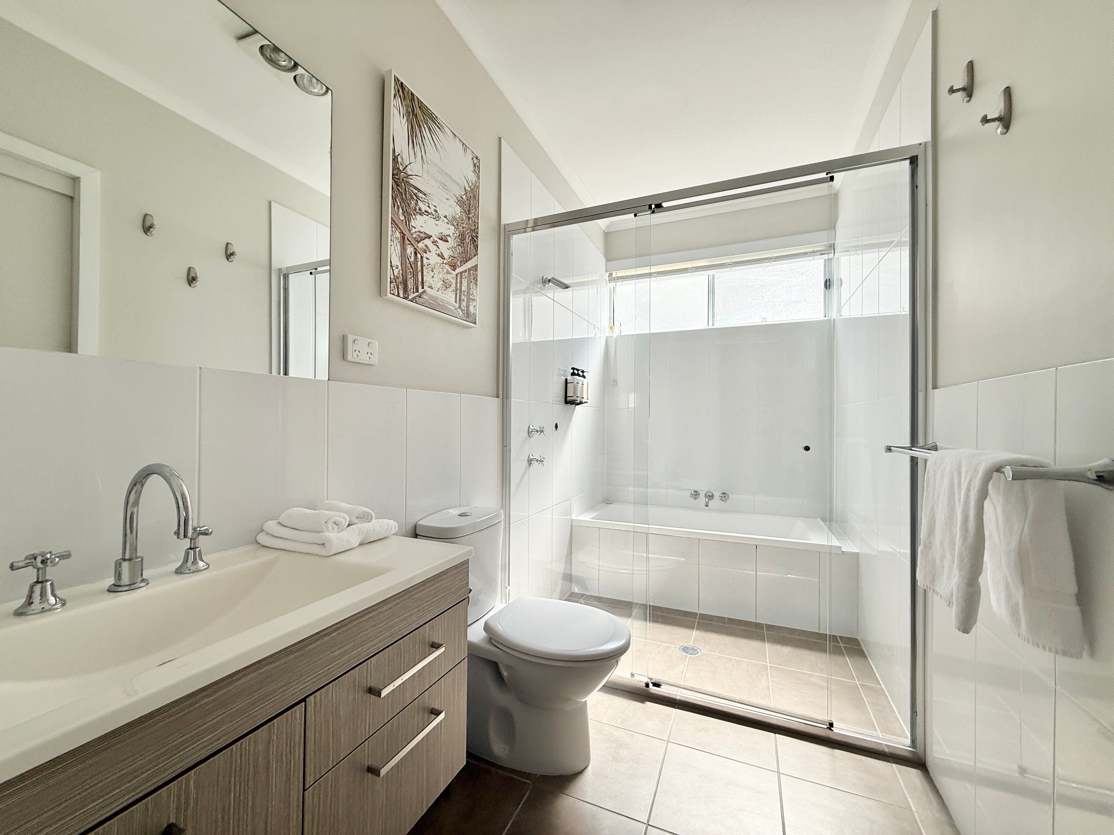 A modern bathroom with a shower, toilet, and vanity.