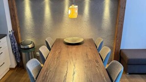 Ein Essbereich mit einem Holztisch, sechs Stühlen und einer hängenden Pendelleuchte.