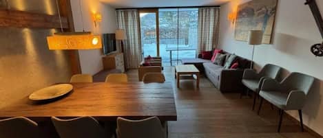 Un salon moderne avec une table à manger en bois, des canapés et une grande fenêtre offrant une belle vue.