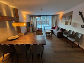 Un soggiorno moderno con un tavolo da pranzo in legno, divani e un'ampia finestra vista panoramica.