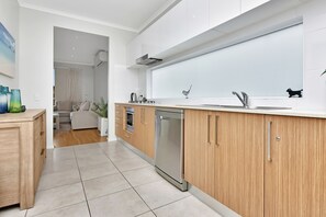 A modern kitchen with wooden cabinets, a stainless steel dishwasher, and a large window above the sink.