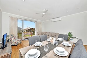 A dining area with a table set for four, a sofa, and a television in the corner.