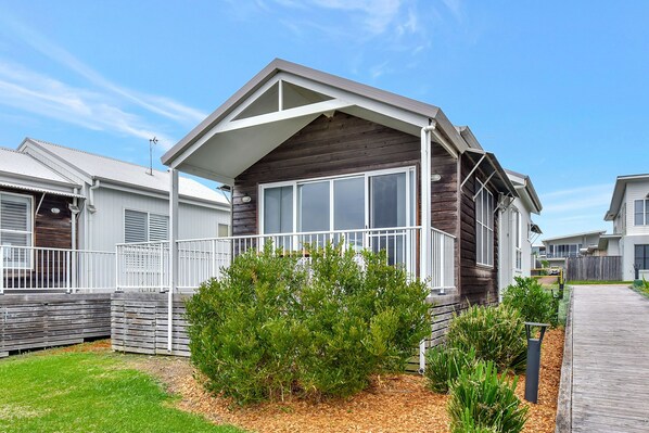 A modern single-story house with a covered porch, a fenced yard, and a well-maintained garden.