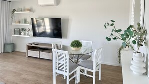 Un soggiorno moderno con una TV a schermo piatto, mobili bianchi e una pianta in vaso.