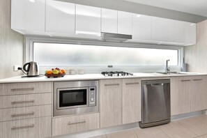 Een moderne keuken met een ingebouwde oven, vaatwasser en een groot raam boven de gootsteen.