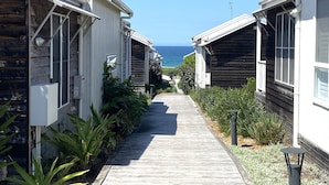 A pathway leading to beachside cabins with a view of the ocean. - Beach Escape at Caves Beach Villas (Caves Beach)