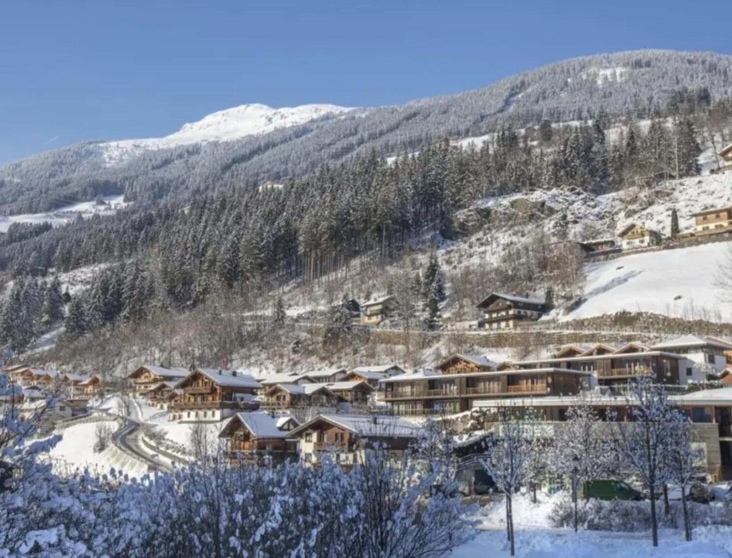 A snow-covered mountain resort with wooden chalets and a ski slope.