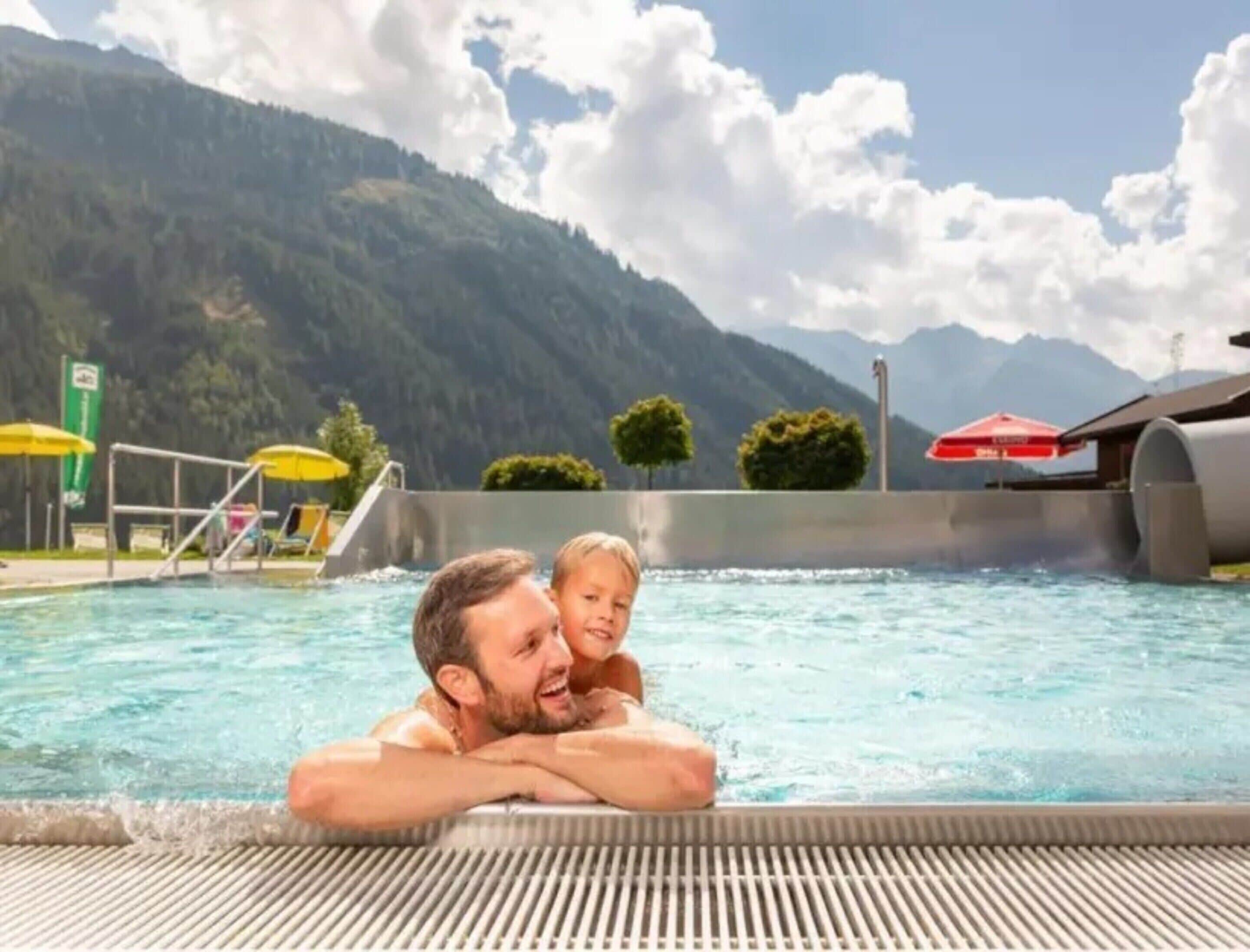 Une piscine avec une vue sur les montagnes, un plongeoir et des parasols.