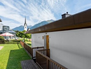 A building with a white exterior and a wooden fence, a clear sky, and a mountain in the background.