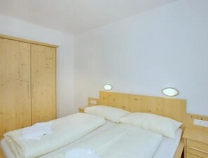A single bed with white bedding in a room with wooden walls and a wooden wardrobe.
