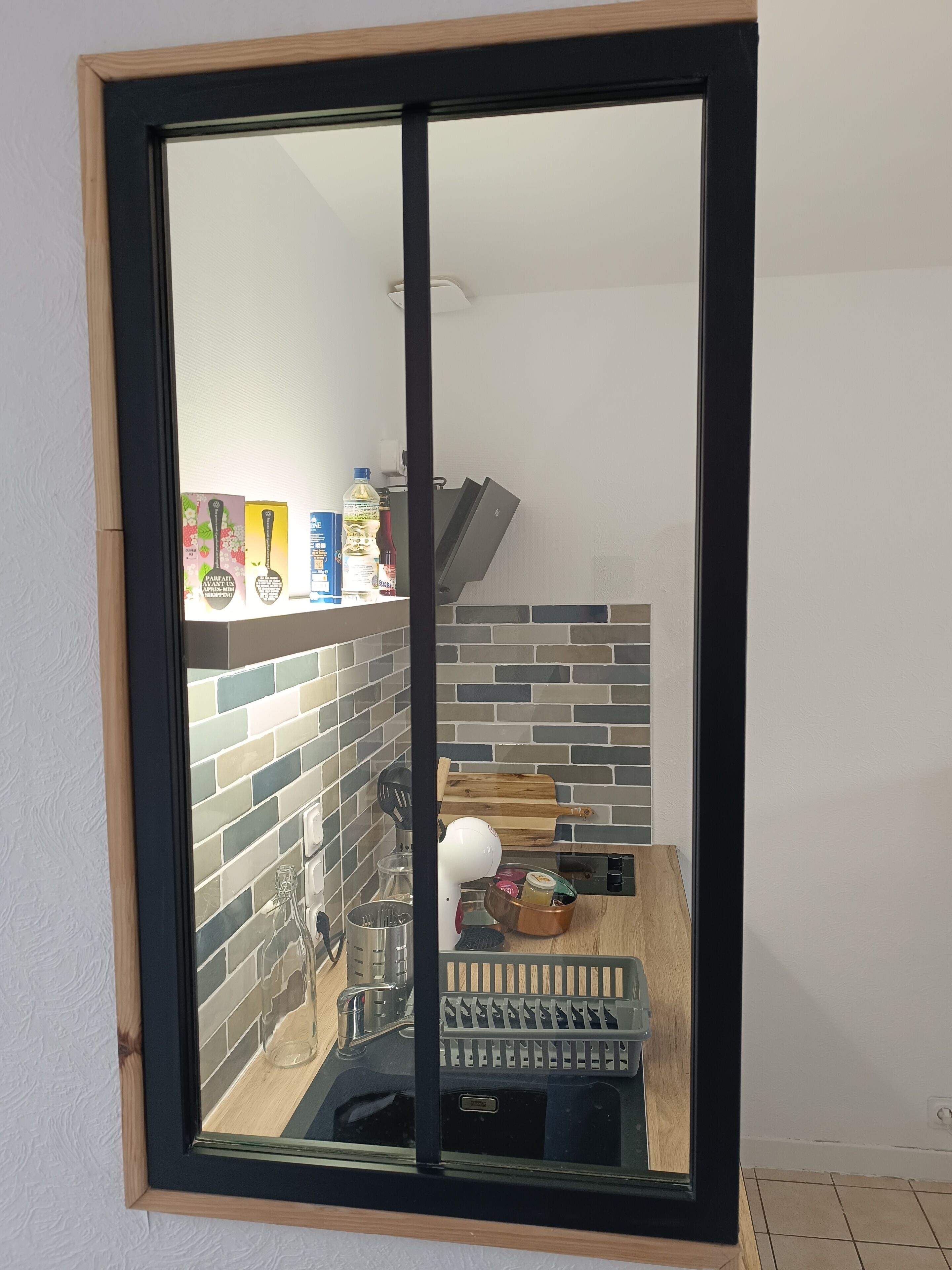 Une cuisine avec un mur recouvert de carreaux, un plan de travail en bois, ainsi que divers appareils et ustensiles de cuisine.