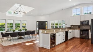 A modern kitchen with white cabinetry, a central island, and a dining area with a table and chairs.
