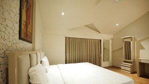 A bedroom with a large bed, a desk, and a mirror. - Sandal Wood Villa By 97RoyalVista (Mawal)