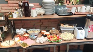 Montaje de bufé con diferentes alimentos, utensilios y una cafetera.