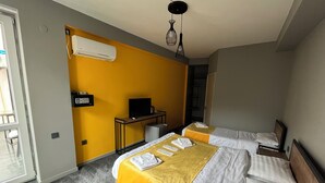 Habitación de hotel con dos camas, un escritorio con televisor y aire acondicionado.
