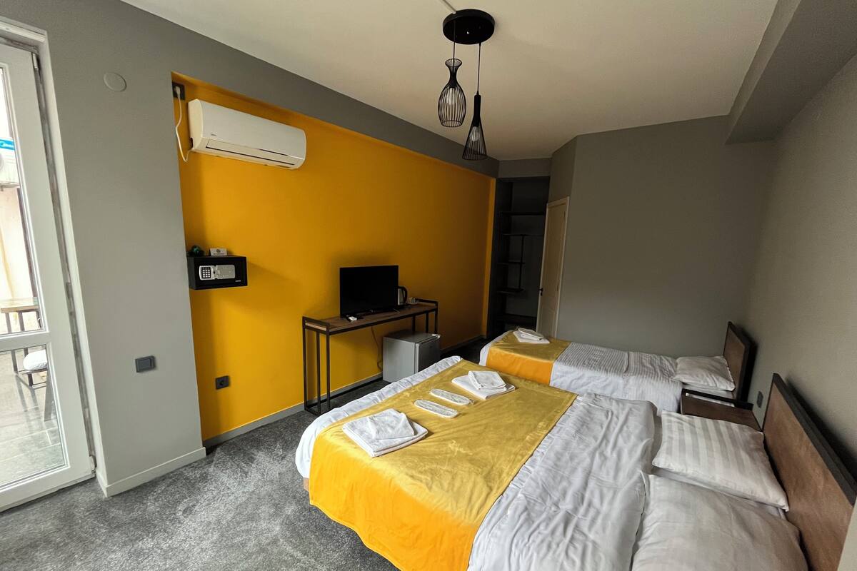 Ein Hotelzimmer mit zwei Betten, einem Schreibtisch und einem Fernseher sowie einer Klimaanlage.