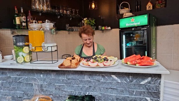 Una zona de bar con un refrigerador Heineken, una bandeja de frutas y un dispensador de bebidas.