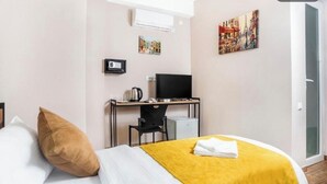 Una habitación de hotel con una cama, un escritorio con computadora, una silla y un televisor.