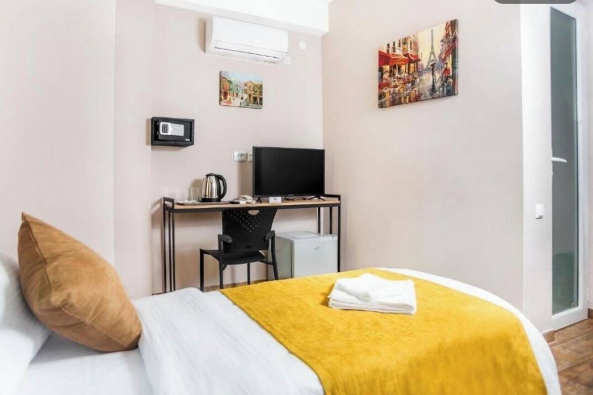 Ein Hotelzimmer mit einem Bett, einem Schreibtisch mit Computer, einem Stuhl und einem Fernseher.