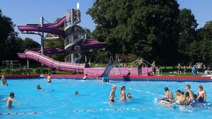 A swimming pool with a water slide and a lifeguard stand. - 3bedroom, heated pool, 20min to beach, kidsproof (Heinkenszand)