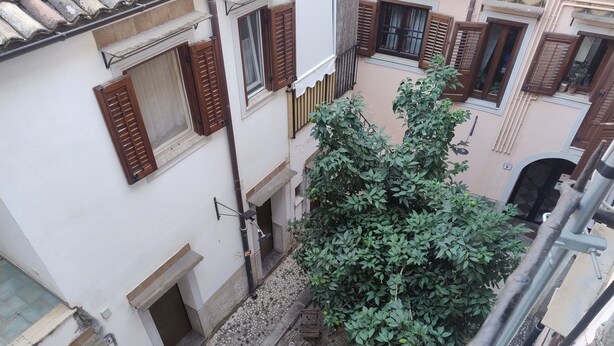 Un callejón estrecho con un árbol y un pequeño espacio al aire libre para sentarse.