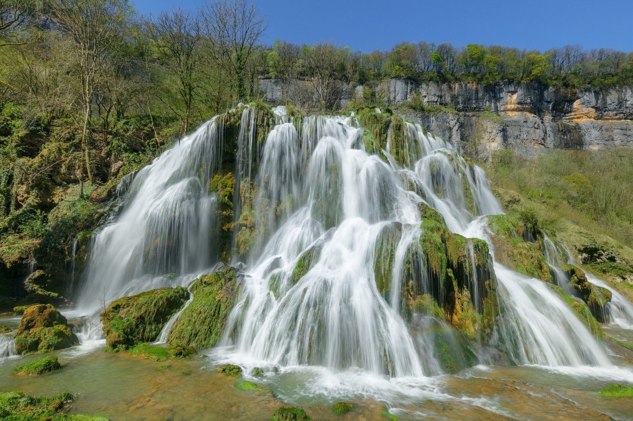 A waterfall cascading over rocky terrain with lush greenery around.