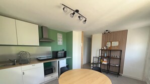 Cocina compacta con microondas, tostadora y lavabo. En primer plano, una mesa de comedor con sillas.