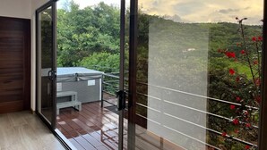A modern room with a sliding glass door leading to a balcony with a view of a lush green landscape. - Nambi Monteverde (Monteverde)
