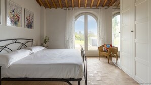 A bedroom with a bed, a chair, and a view of the outdoors.